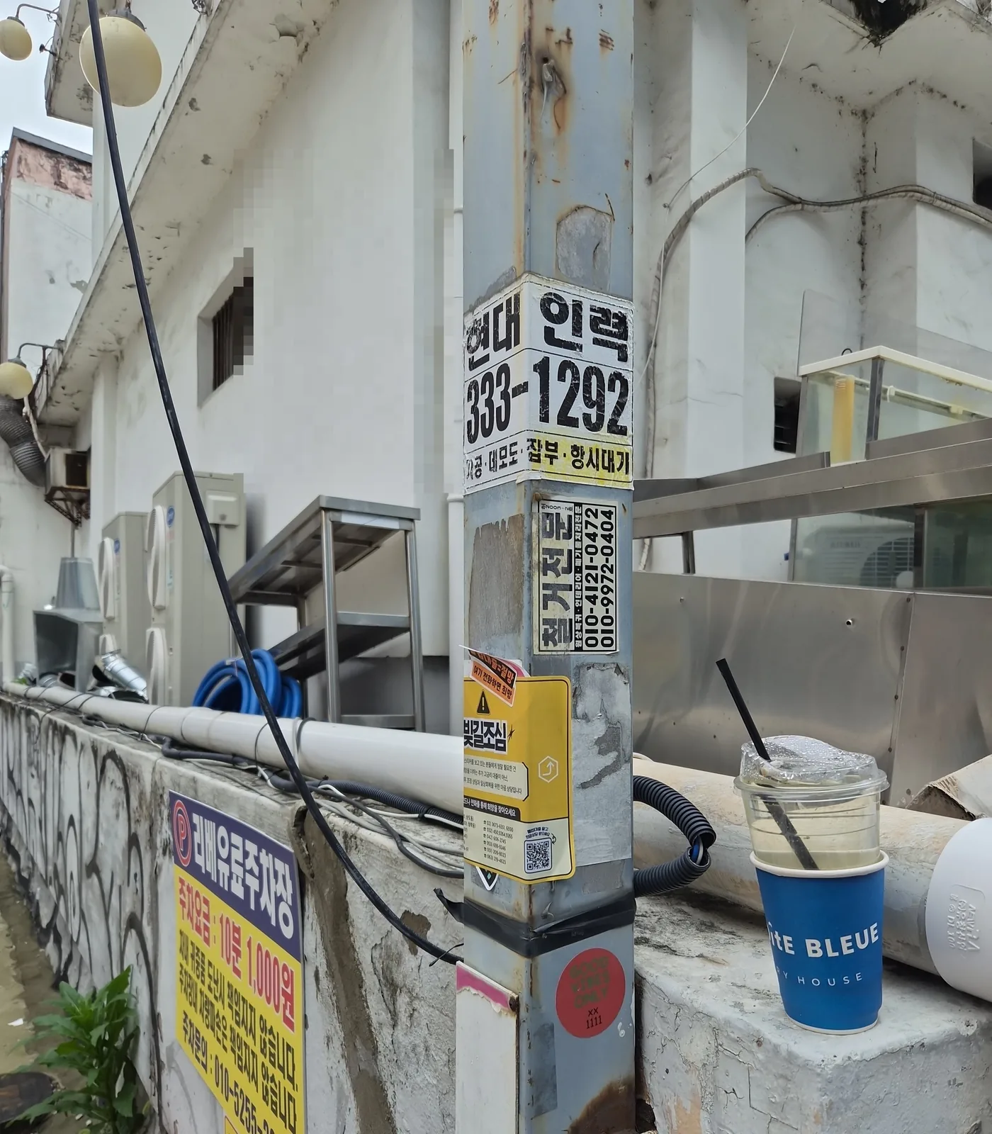 가로 기둥에 겹겹이 붙은 불법 스티커 — 제거 전(연락처는 모자이크 처리)