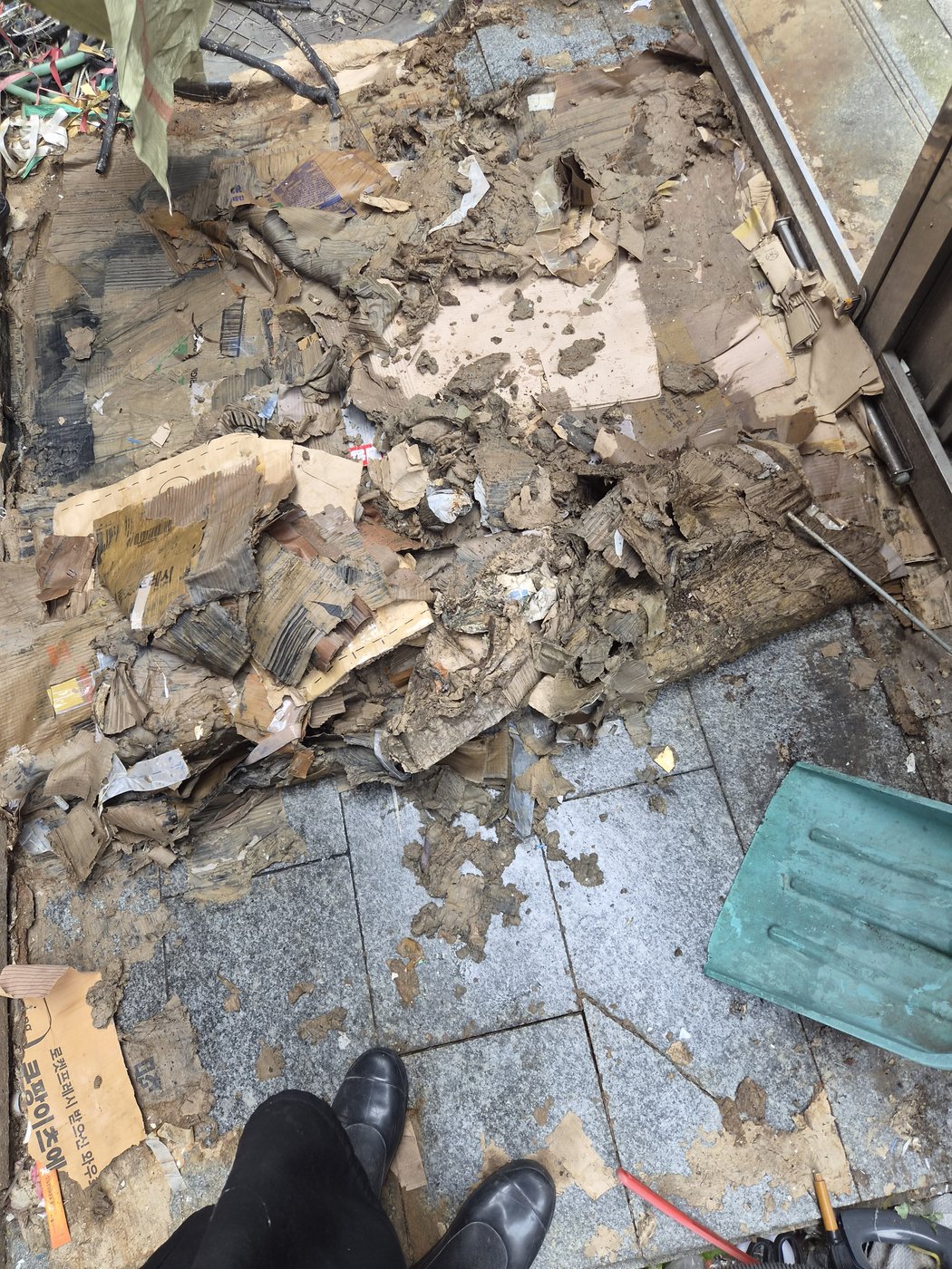 젖은 폐지가 눌어붙어 삽으로 떠내야 하는 현관 바닥