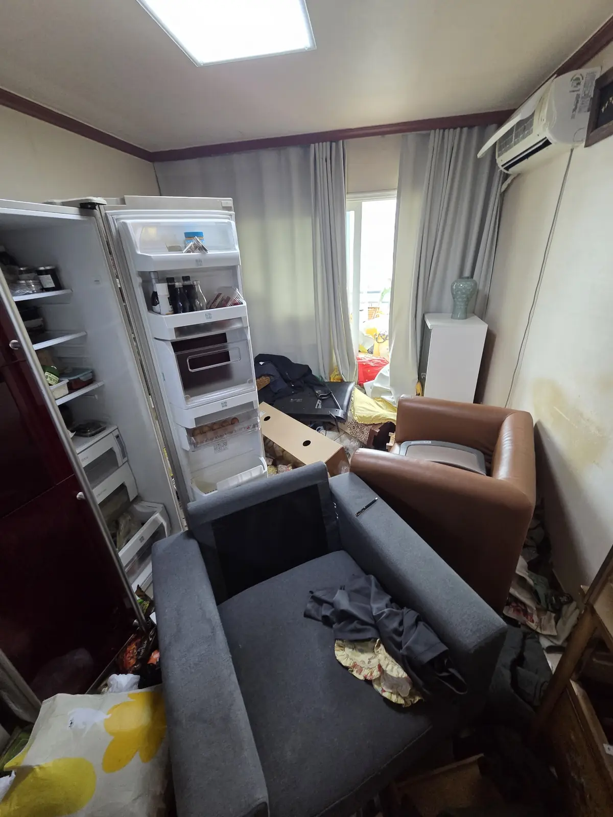 거실 소파와 냉장고 주변까지 물건이 밀려 올라온 아파트 짐정리 전 상태