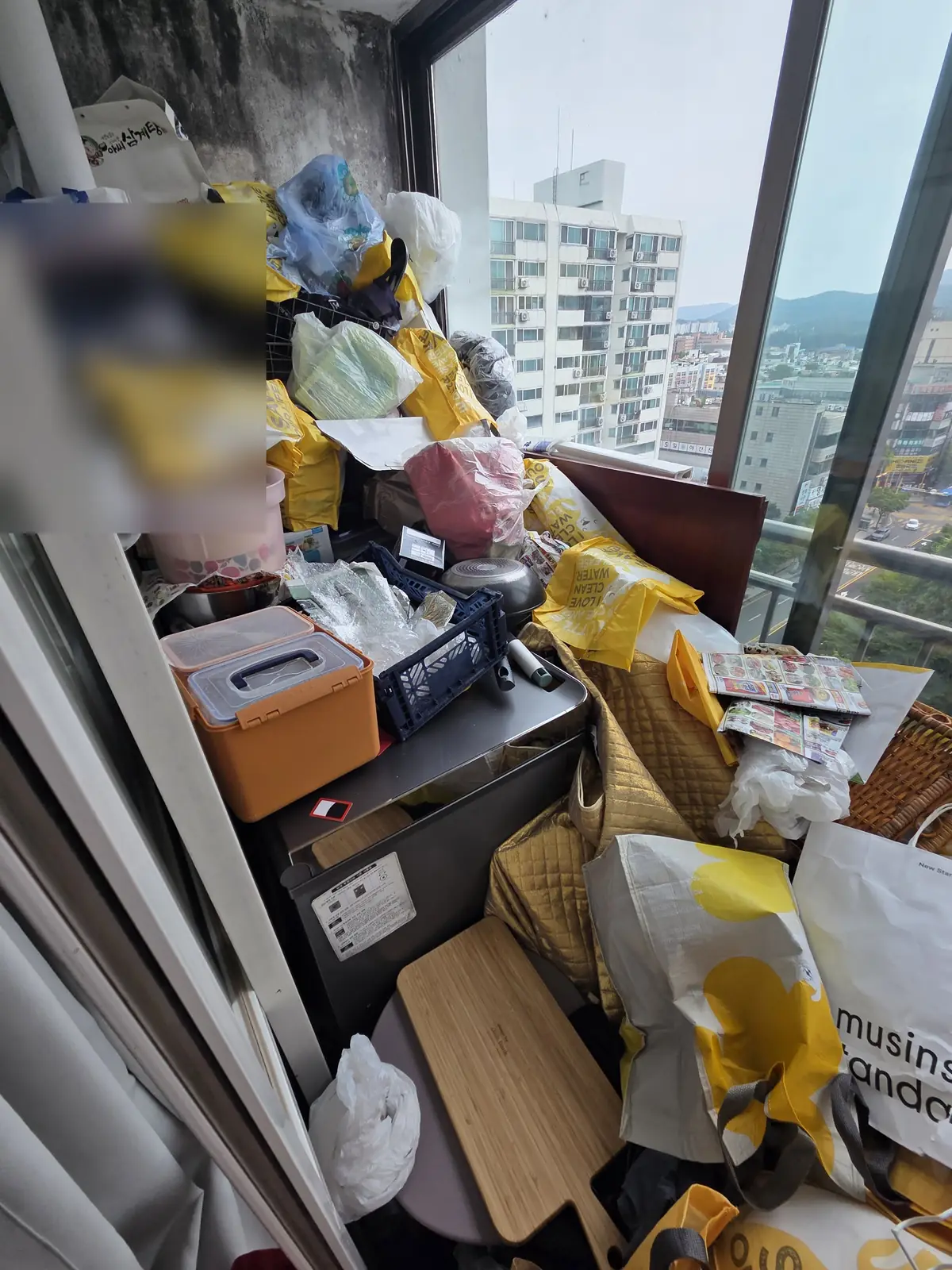 베란다 구석까지 봉지와 상자가 겹겹이 쌓이고 벽면 상단에 곰팡이 자국이 번진 상태