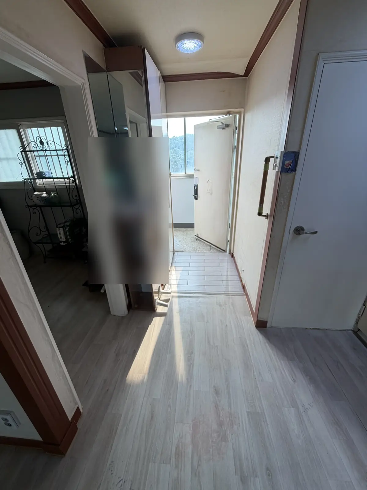 짐정리와 청소를 마친 아파트 현관 복도 — 바닥이 드러나고 통로가 확보된 작업 후 상태