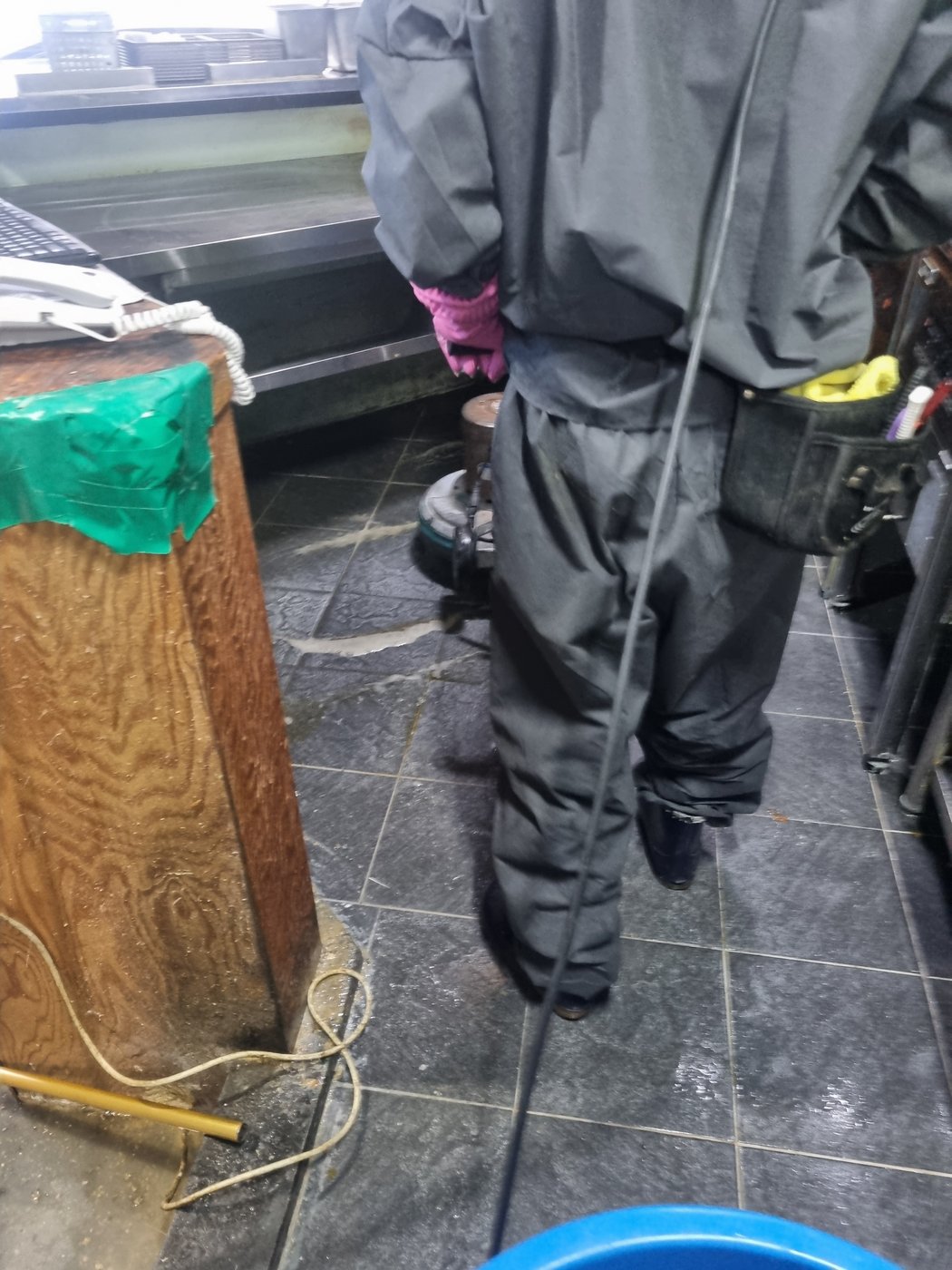 작업자가 주방 통로 바닥을 폴리셔로 세정하는 뒷모습