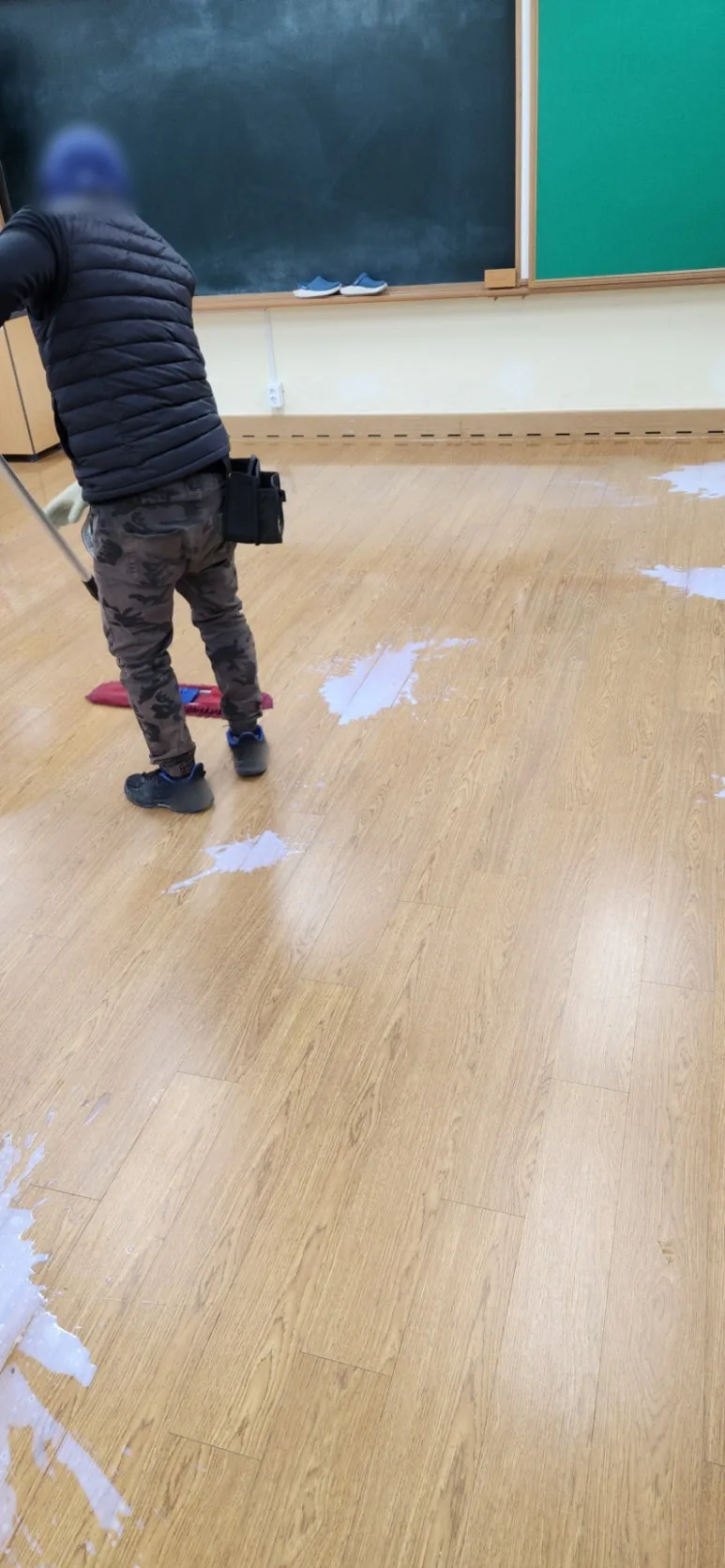 칠판 앞 교실 바닥 곳곳에 흰 왁스를 부어 두고 작업자가 붉은 밀대로 넓게 펴 나가는 뒷모습
