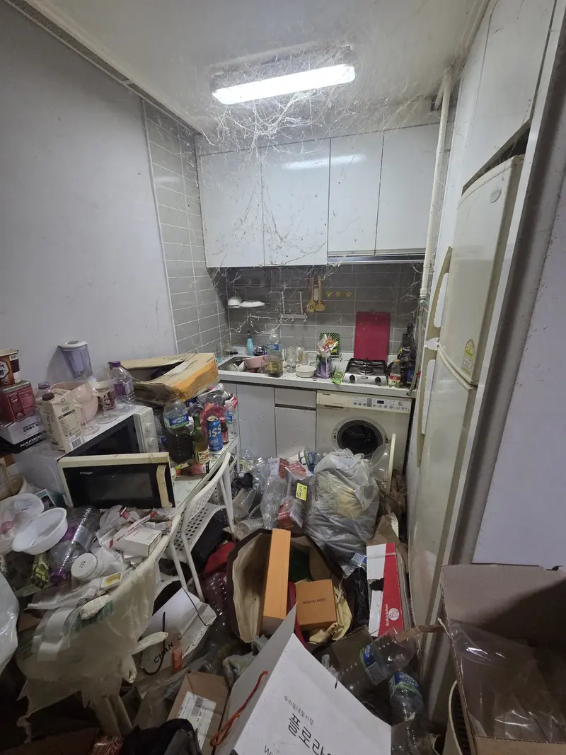 상부장과 천장까지 거미줄이 늘어지고 조리대와 바닥이 음식물 포장재로 뒤덮인 주방 작업 전 상태