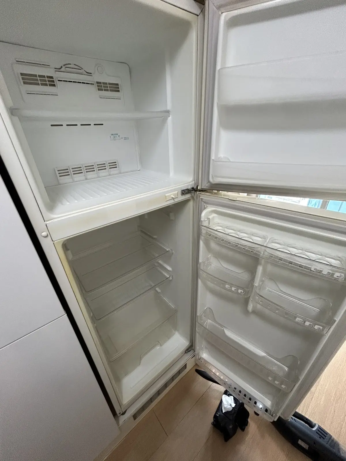 내용물을 모두 비우고 안쪽을 세정한 뒤 문을 열어 말리고 있는 냉장고 — 작업 후 상태