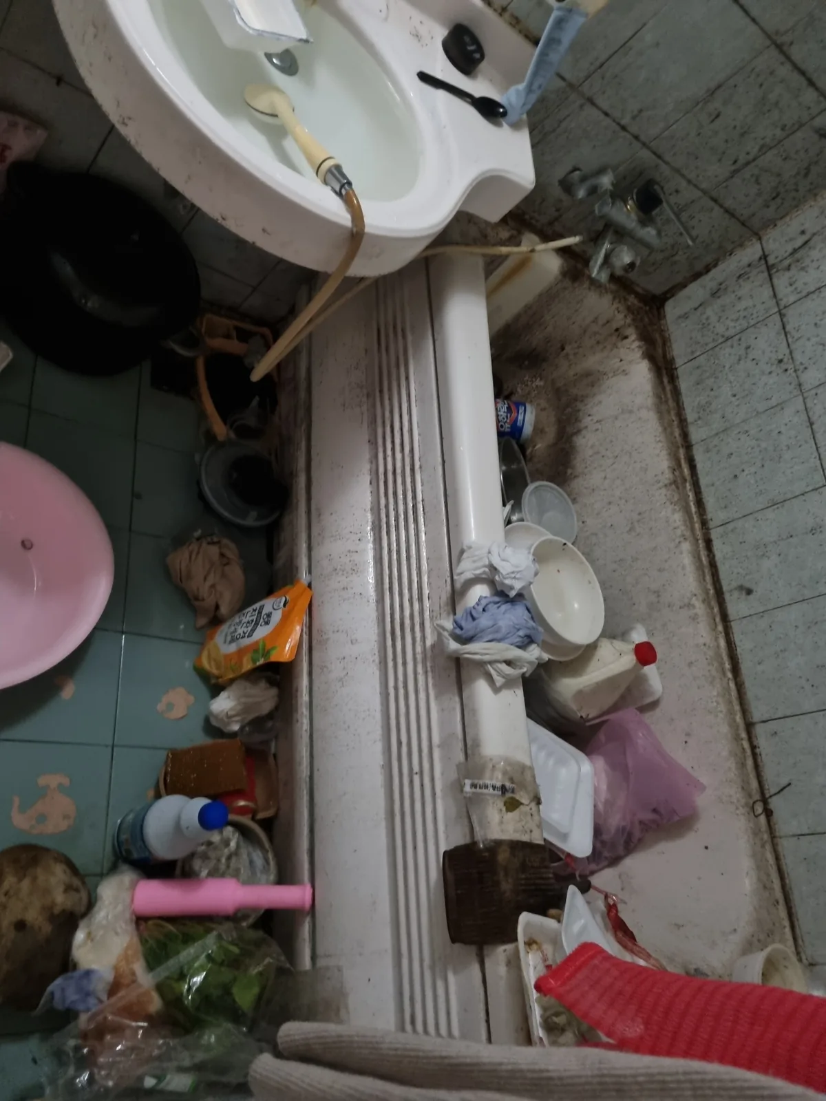 화장실 바닥에 용기와 잡동사니가 놓인 상태 — 배수구 주변까지 물건이 쌓인 현장