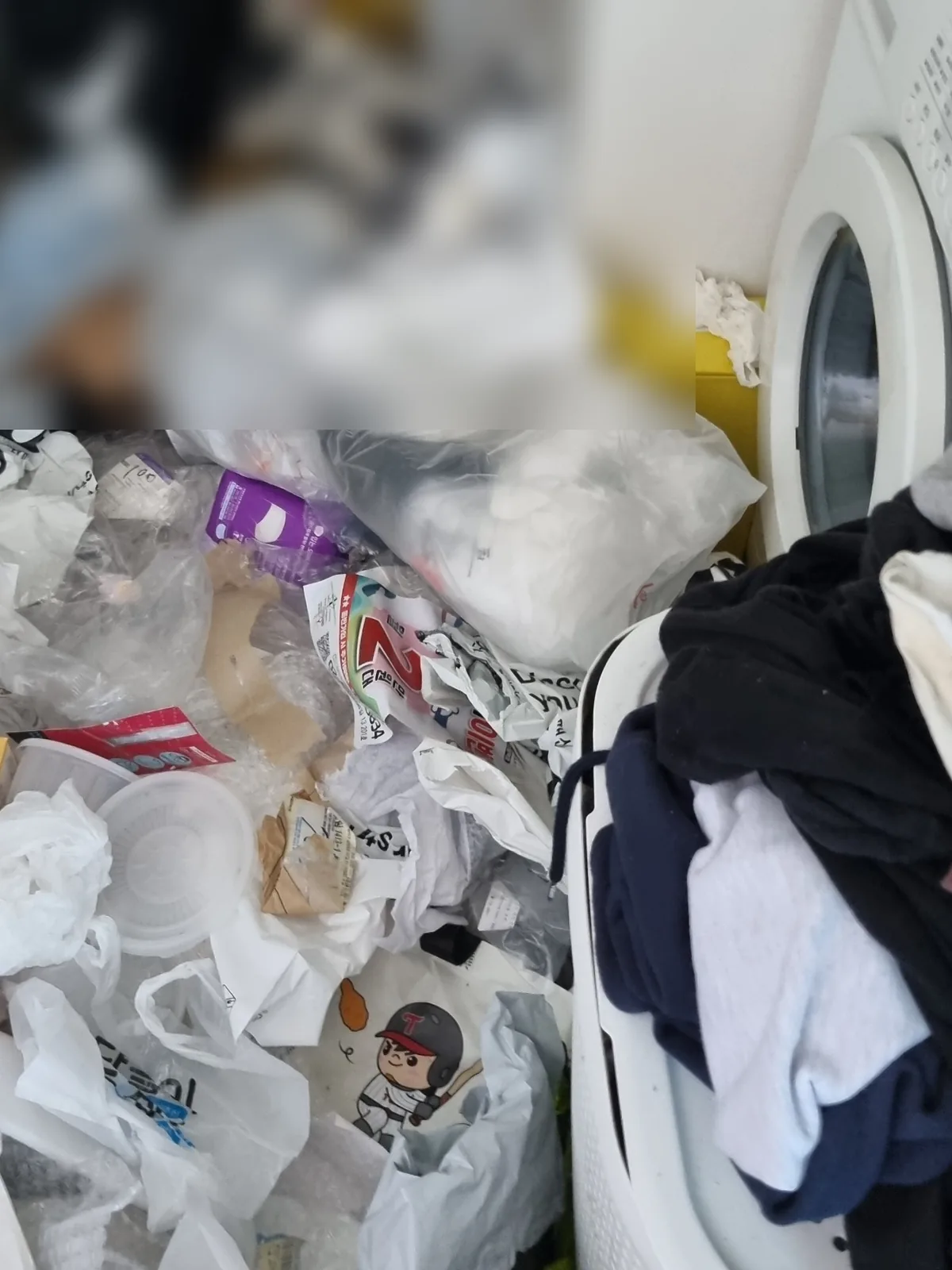 현관에서 세탁 공간으로 이어지는 통로가 봉투로 막힌 상태 — 출입 동선부터 확보해야 하는 현장