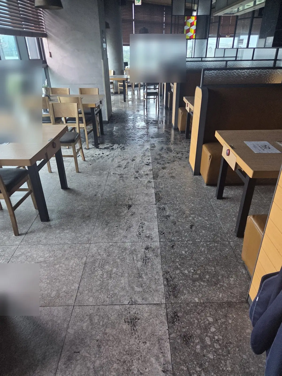 식당 화재 진화 후 소방수와 그을음이 섞인 검은 오염수가 홀 바닥에 퍼지고 통로를 따라 발자국 궤적이 남은 작업 전 상태