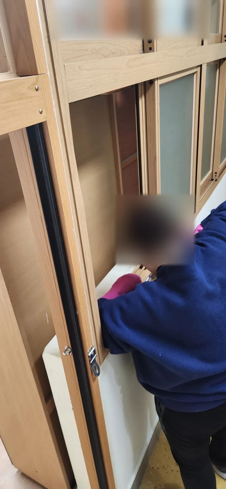 나무 수납장 미닫이문을 열어 두고 작업자가 몸을 숙여 문틀 안쪽과 레일을 닦는 모습
