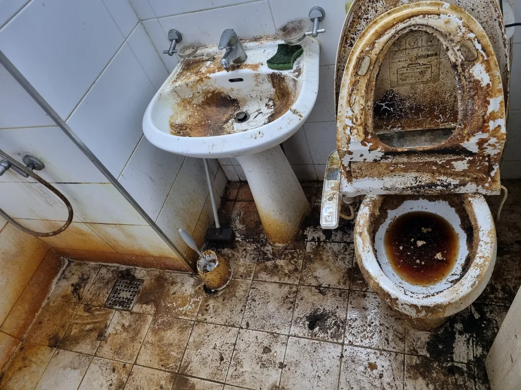 오래 방치된 화장실 변기와 세면대 — 물때와 오염이 겹겹이 굳어 자국이 남은 상태
