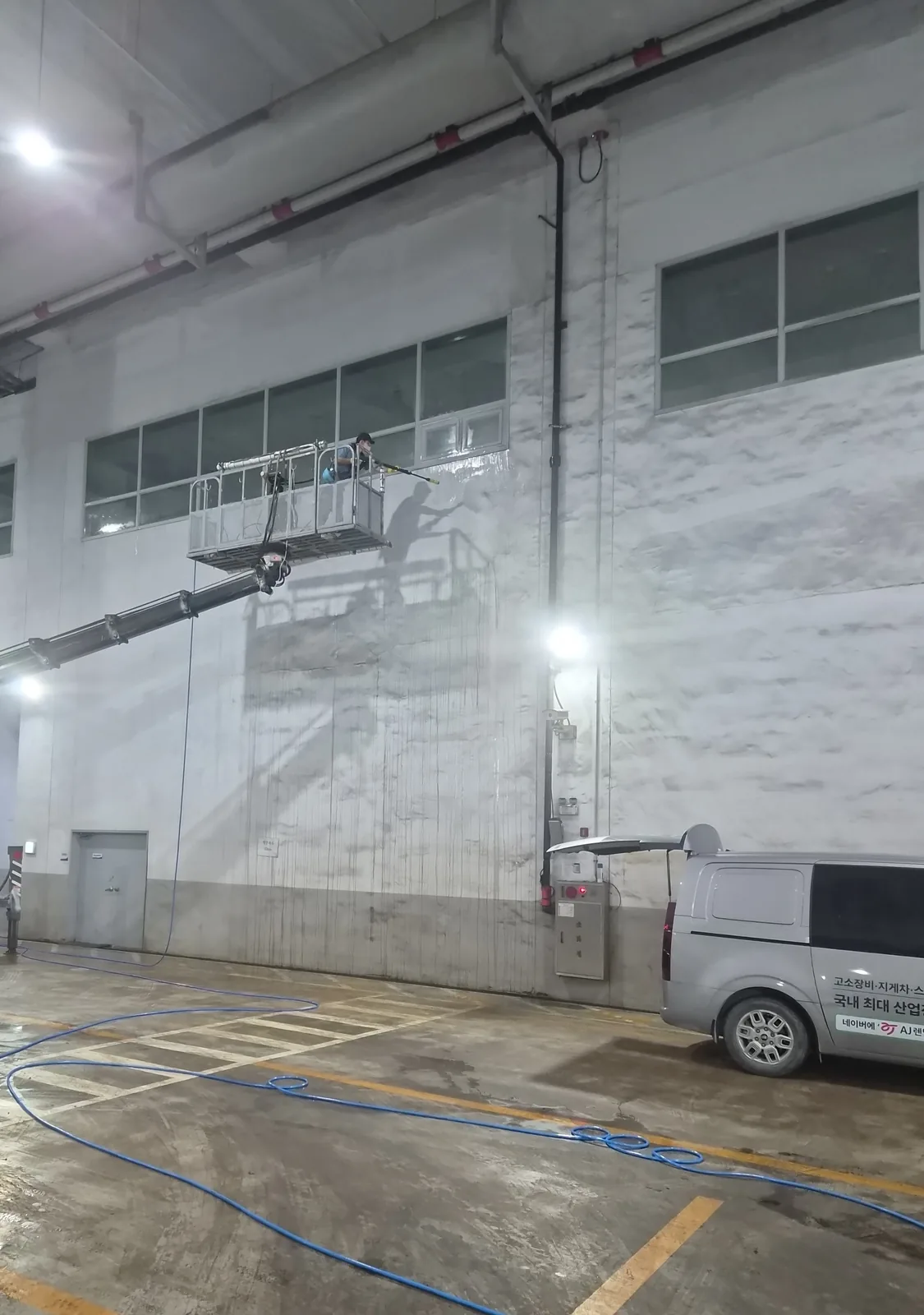 고소 창 라인 옆 벽면을 고압세척하는 중 — 세척된 면과 매연 얼룩 면의 대비