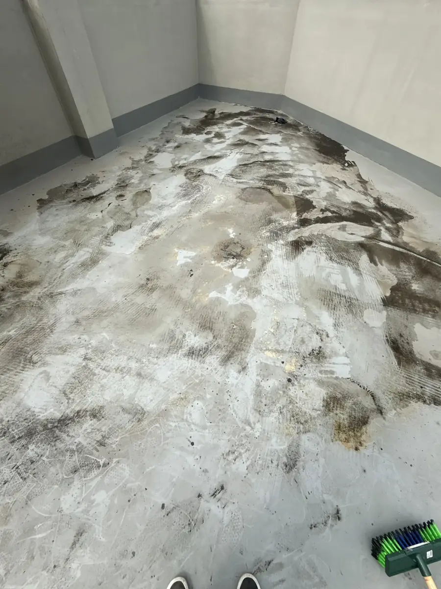 안양 상가 건물 옥상 청소 전 — 식당 후드 배기관에서 배출된 유증기·기름 미스트가 옥상 바닥에 검은 기름때로 두껍게 굳어 있는 모습. 발자국·호스 자국까지 박혀 일반 청소 불가능 상태