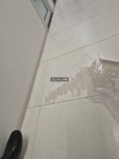 오수 역류 바닥 청소 작업 중 — 젖은 바닥 오수를 걷어내고 세정하는 작업